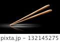Elegant wooden chopsticks resting on a reflective surface in dark setting 132145275