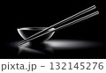 Stylish black bowl with chopsticks on a sleek surface in a dark setting 132145276