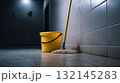 Cleaning supplies in a dimly lit corridor with tiled walls 132145283