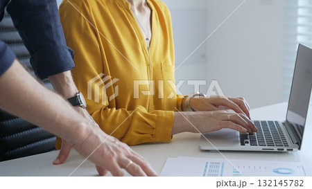 Colleagues are collaborating on a project, analyzing financial charts and using a laptop to input data, working together to achieve their business goals. Business people concept 132145782