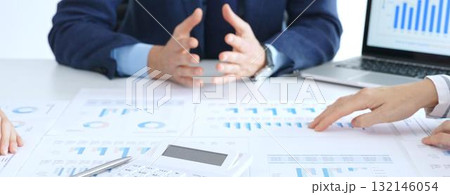 Business people reviewing financial charts and reports in office, using a laptop and calculator while engaging in discussions about strategy and performance Business people reviewing financial charts and reports in office, using a laptop and calculator while engaging in discussions about strategy and performance 132146054