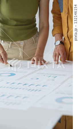 Business professionals analyzing financial reports, pointing at charts during collaborative meeting, discussing data with focused professional demeanor Business professionals analyzing financial reports, pointing at charts during collaborative meeting, discussing data with focused professional demeanor 132146154