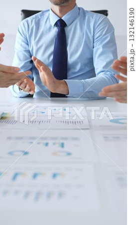 Business team meeting with charts and documents on desk discussing financial strategy, planning corporate growth, analyzing market data and performance reports 132146190