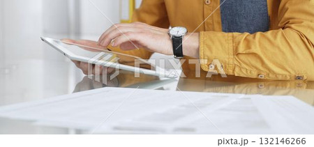 Person using a digital tablet for business at desk, navigating online content or browsing documents. Audit and taxes in business 132146266