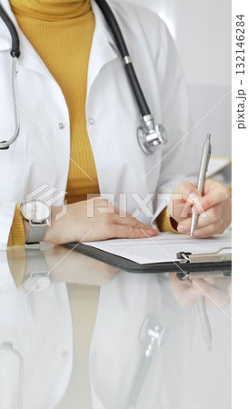 Female physician or medic completing paperwork, preparing a diagnosis, or providing healthcare service in a clean modern office. Medicine, healthcare and science concept Female physician or medic completing paperwork, preparing a diagnosis, or providing healthcare service in a clean modern office. Medicine, healthcare and science concept 132146284