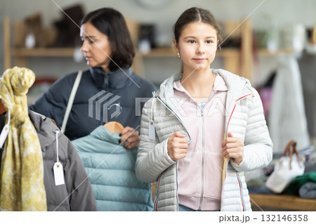 Teenage girl with her mother try on down jacket Teenage girl with her mother try on down jacket 132146358