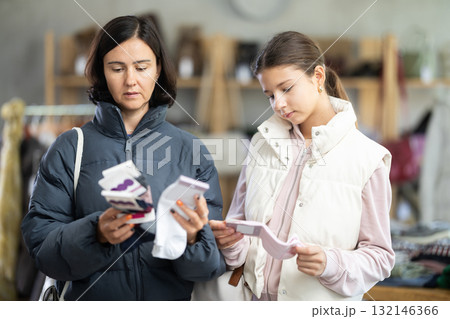 Mother and teen daughter looks at products in store and selects cotton socks. Mother and teen daughter looks at products in store and selects cotton socks. 132146366