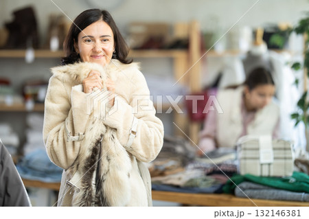 Adult woman trying on fur coat in store 132146381