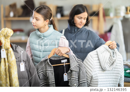 Teenage girl with her mother chooses coat or down jacket 132146395