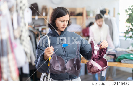 Woman looks at products in store and selects bra. Family shopping Woman looks at products in store and selects bra. Family shopping 132146487
