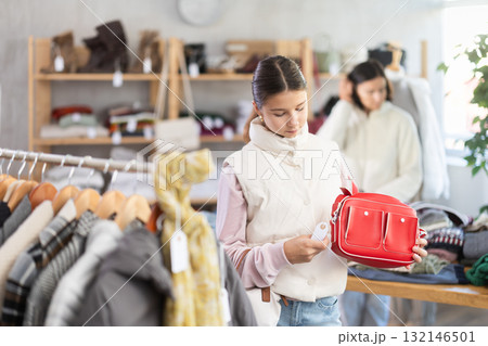 Teenage girl choosing handbag in clothing store 132146501