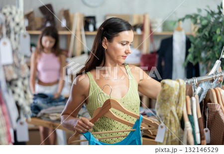 Middle-aged woman choosing something for summer in clothing store Middle-aged woman choosing something for summer in clothing store 132146529