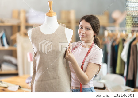 Woman seamstress adjusts clothes on mannequin 132146601