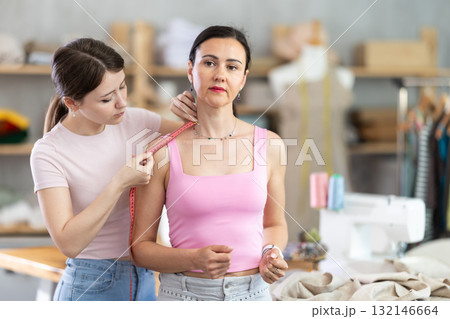 Girl designer measures woman client 132146664