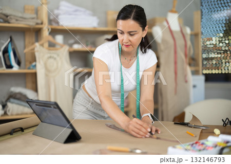 Woman dressmaker makes pattern using drawing on tablet Woman dressmaker makes pattern using drawing on tablet 132146793