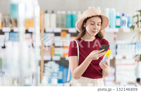 Woman in pharmacy scans QR code on insect repellent 132146809