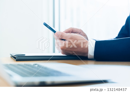 スマホを操作するビジネスマンの手元 132148437