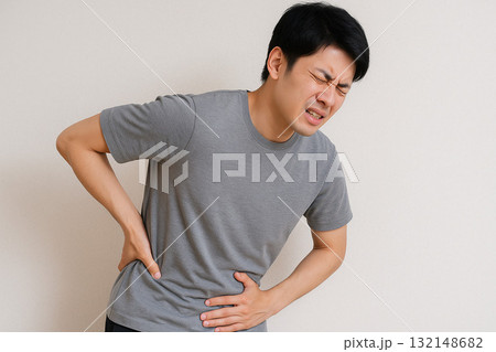 腰に手を当ててつらそうな表情をする人 132148682