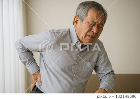 腰に手を当ててつらそうな表情をする人 132148690