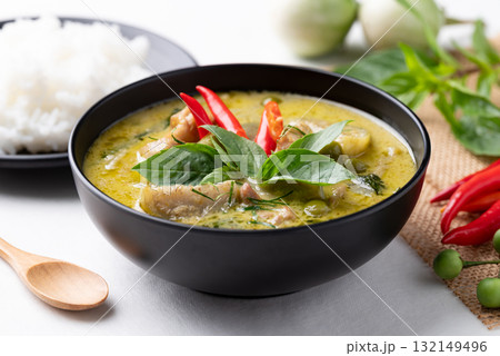 Thai green curry chicken in black bowl with rice and ingredients on white background 132149496
