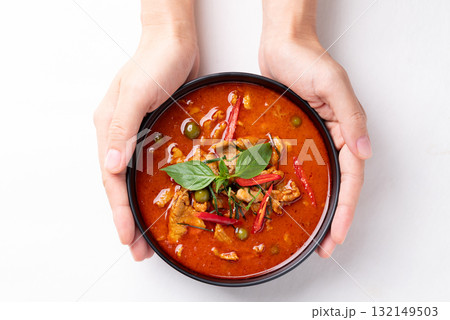 Thai red curry with pork in black bowl holding by hand on white background 132149503
