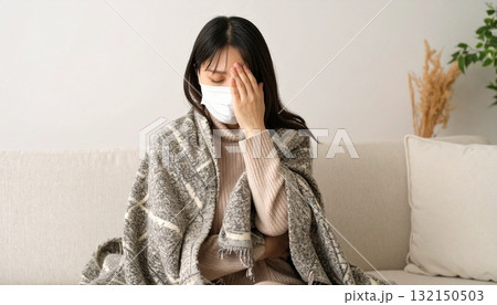 マスクをして頭を抑える女性・熱をはかる マスクをして頭を抑える女性・熱をはかる 132150503