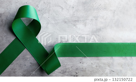 Mental Health Awareness Concept. Green Ribbon lay on Grey background Mental Health Awareness Concept. Green Ribbon lay on Grey background 132150722