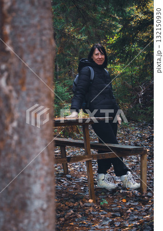 Girl in autumn forest. Young woman with backpack in mountain woodland. Active lifestyle concept. Hiking woman. Journey in Carpathian mountains, Ukraine. Tourist woman in woods. Explore the world. 132150930