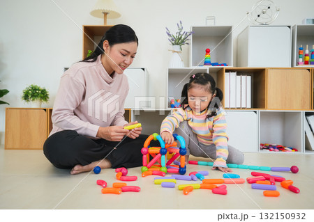 toddler girl and mother playing colorful magnetic construction toy at home 132150932