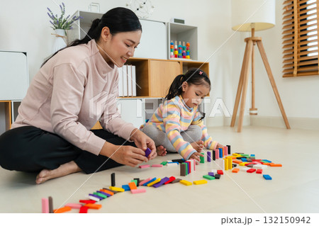 toddler girl and mother playing colorful wooden block toy or domino game together toddler girl and mother playing colorful wooden block toy or domino game together 132150942