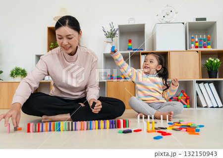 toddler girl and mother playing colorful wooden block toy or domino game together toddler girl and mother playing colorful wooden block toy or domino game together 132150943