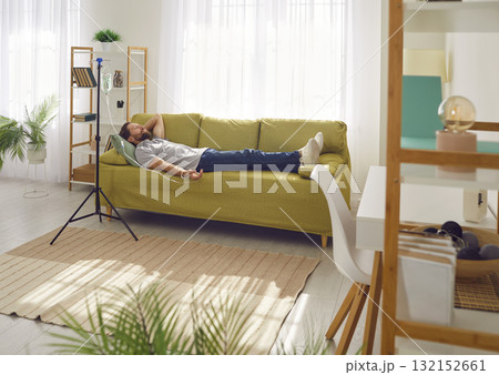 Happy, relaxed man getting an intravenous vitamin injection on the couch at home 132152661