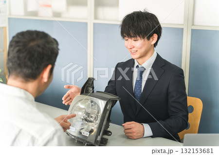 自動車整備工場の受付で接客をするサービスフロントの男性と顧客の男性 132153681