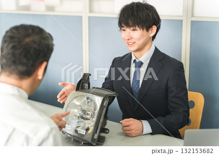 自動車整備工場の受付で接客をするサービスフロントの男性と顧客の男性 132153682