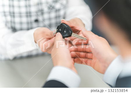 受付で車の鍵の受け渡しをする女性スタッフと顧客の男性 受付で車の鍵の受け渡しをする女性スタッフと顧客の男性 132153854
