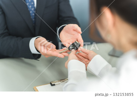 受付で車の鍵の受け渡しをする男性スタッフと顧客の女性 132153855