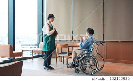 車椅子に乗った男性を接客する飲食店店員 車椅子に乗った男性を接客する飲食店店員 132153920