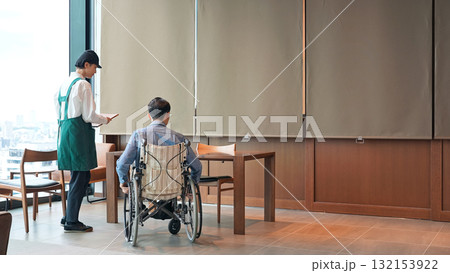 車椅子に乗った男性を接客する飲食店店員 車椅子に乗った男性を接客する飲食店店員 132153922