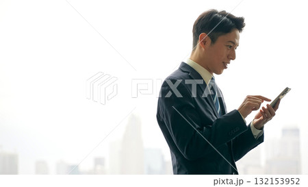 都市を背景にスマホを使う男性ビジネスパーソン 都市を背景にスマホを使う男性ビジネスパーソン 132153952