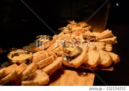 A beautifully arranged Assorted Bread Platter featuring a variety of Spreads on a Wooden Countertop 132154252