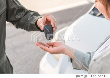 女性客から車の鍵を預かる自動車整備士の男性スタッフ 女性客から車の鍵を預かる自動車整備士の男性スタッフ 132154418
