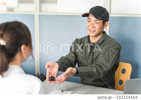 女性客に車の鍵を渡す自動車整備士の男性スタッフ 132154564