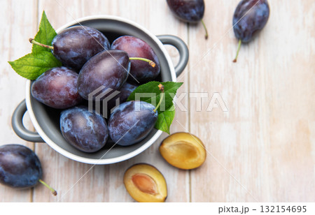 Fresh ripe plums in bowl on wooden table 132154695