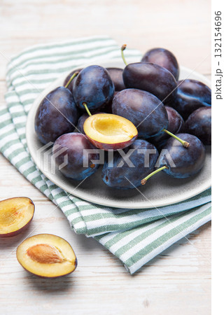 Fresh ripe plums in grey bowl on wood table 132154696