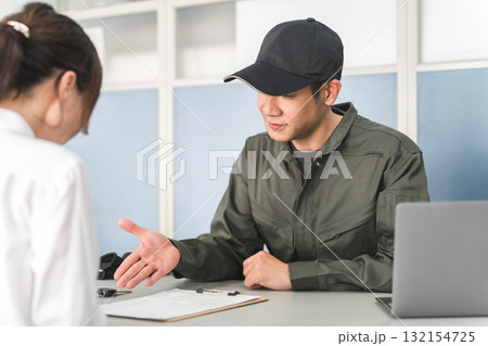 自動車整備工場の受付で説明・見積もり・提案をする整備士の男性と顧客の女性 132154725