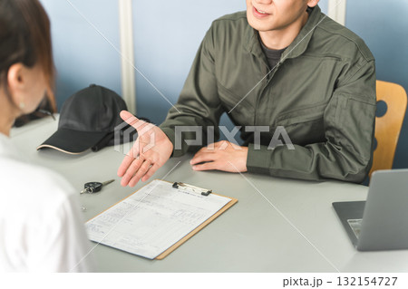 自動車整備工場の受付で説明・見積もり・提案をする整備士の男性と顧客の女性 132154727