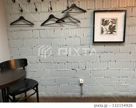 Cozy industrial cafe wall with empty hangers, framed plant art, table and chairs, background Cozy industrial cafe wall with empty hangers, framed plant art, table and chairs, background 132154926