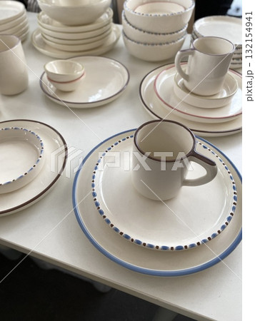 Ceramic tableware with minimalist design on display, featuring plates, bowls, and mugs Ceramic tableware with minimalist design on display, featuring plates, bowls, and mugs 132154941