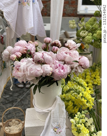 Peonies and flowers at outdoor market display with embroidered textiles 132154942