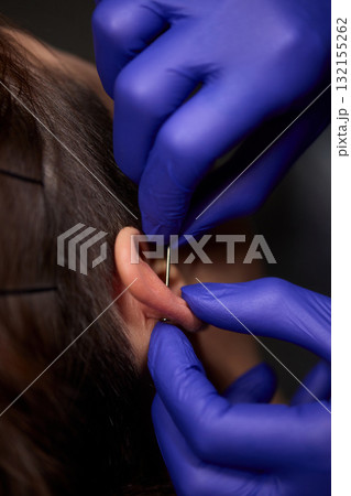 Professional Piercing Process A detailed closeup view showcasing the art of Ear Piercing Professional Piercing Process A detailed closeup view showcasing the art of Ear Piercing 132155262